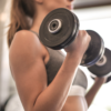 Woman performing dumbbell bicep curls at gym
